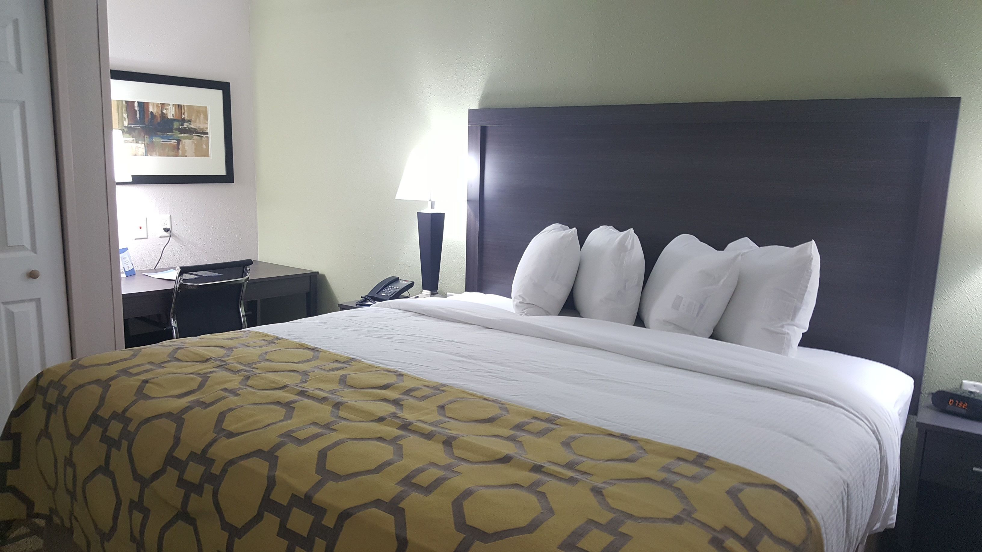 A hotel room with a large bed, a desk, and a chair.
