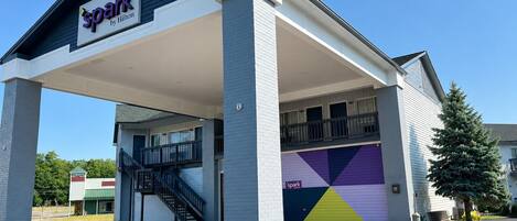 A hotel with a covered entrance, a staircase, and a colorful garage door.