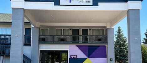 A hotel with a 'spark by Hilton' sign, a two-story structure, and a colorful geometric design on the facade.
