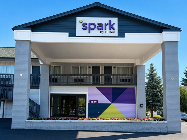 Un hotel con un letrero de 'spark by Hilton', una estructura de dos pisos y un diseño geométrico colorido en la fachada.