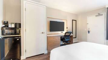 Habitació d'hotel amb un llit, un escriptori amb un ordinador, un microones i un frigorífic.