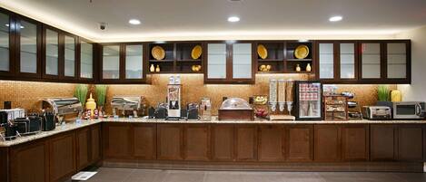 A modern kitchen with a central island, equipped with a coffee machine, toaster, and food dispensers.
