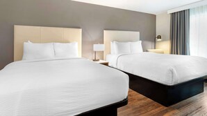 A hotel room with two beds, a nightstand with a lamp, and a window with curtains.
