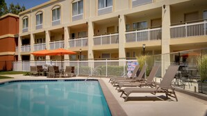 A hotel with a swimming pool, outdoor seating, and multiple balconies.
