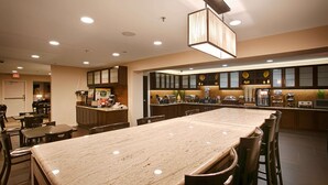 Ein Speisesaal eines Hotels mit einem langen Tisch, Stühlen, einer Buffettheke und einer Kaffeestation.