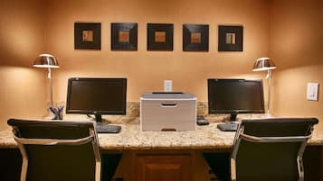 A workspace with two monitors, a printer, and two chairs.