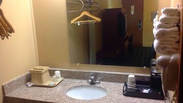 A hotel bathroom with a sink, mirror, towel rack, and a hairdryer.