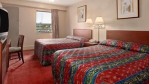 A hotel room with two beds, a desk, and a chair. There are two bedside tables with lamps. - Hilltop Inn (Pittsburgh)