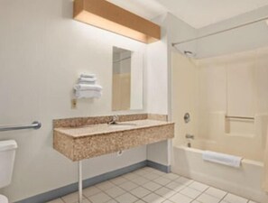 A bathroom with a sink, mirror, towel rack, and a shower area.