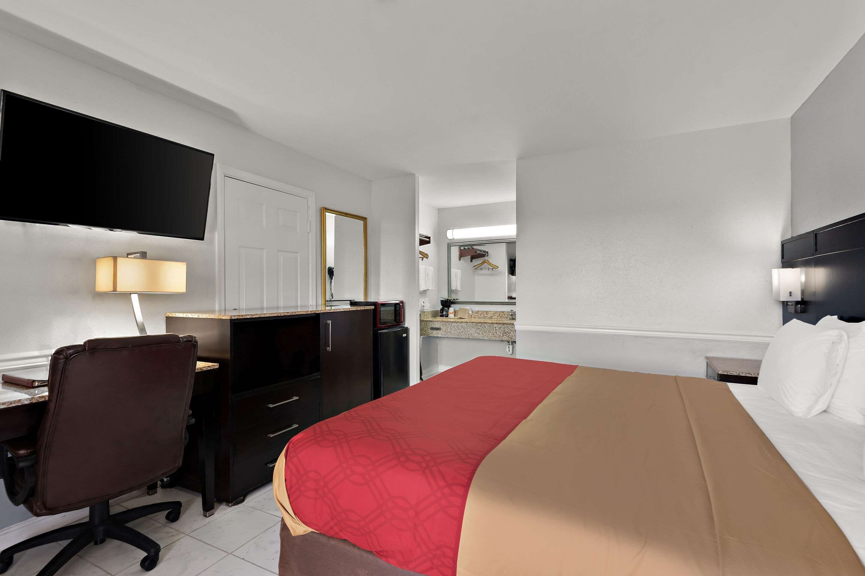 Une chambre d’hôtel équipée d’un lit, d’un bureau, d’une chaise, d’une télévision et d’une kitchenette.