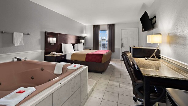 A hotel room with a large bathtub, a double bed, a desk, and a chair.