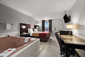 Une chambre d’hôtel avec une grande baignoire, un lit double, un bureau et une chaise.