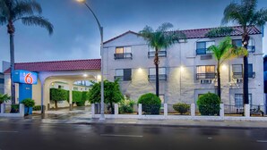 A hotel with a red-tiled roof, multiple balconies, and a well-lit entrance. - Motel 6 Inglewood, CA (Inglewood)