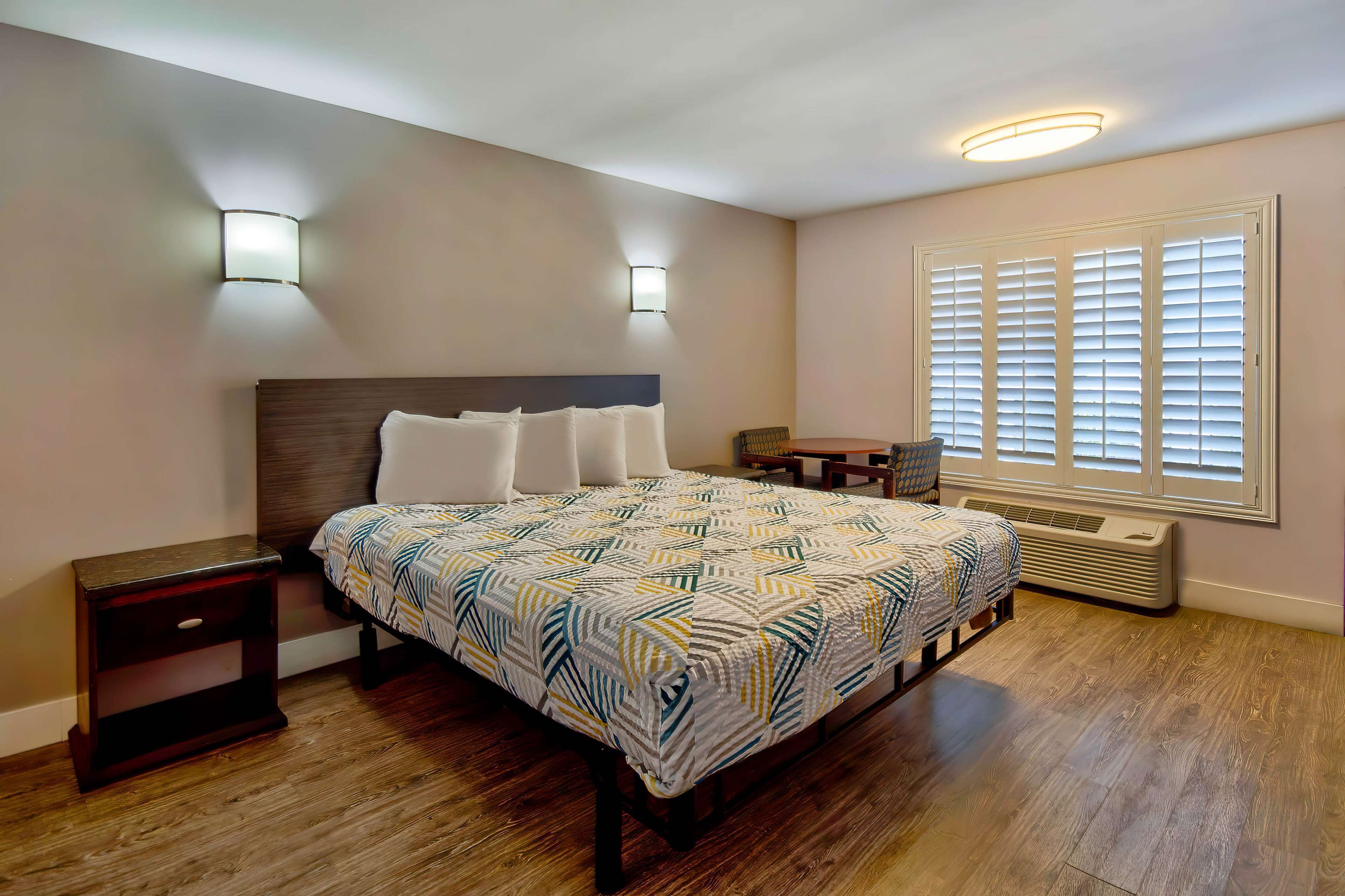 Een slaapkamer met een bed, nachtkastjes, een verwarming en een raam met zonwering.