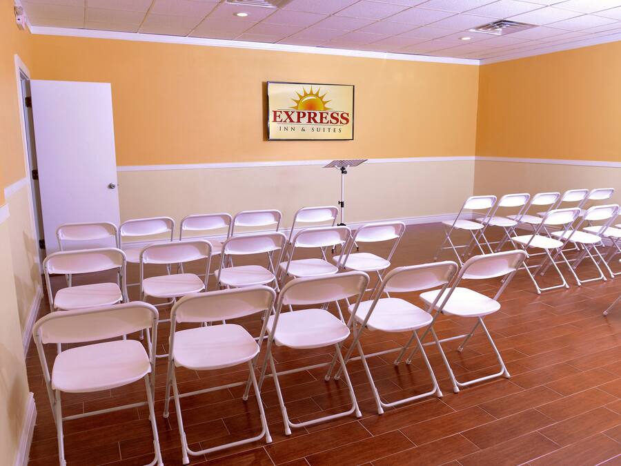 A hotel room with a row of white folding chairs and a ceiling fan.