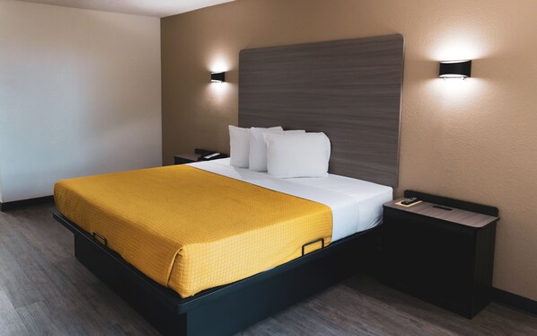 A hotel room with a bed, bedside tables, and a headboard.