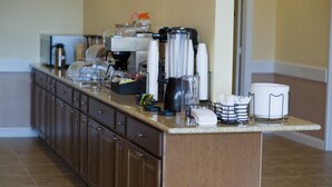 Un comptoir de cuisine avec une machine à café, des tasses et une cafetière.