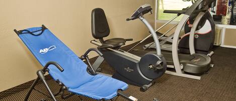 A gym with exercise equipment including a stationary bike, a treadmill, and a blue exercise chair.