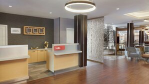 A modern hotel reception area with a reception desk, a 'hello' sign, and a wall-mounted sign for 'Marriott Bonvoy'. - TownePlace Suites by Marriott London (London)