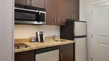 Una cocina compacta equipada con microondas, cafetera y refrigerador.