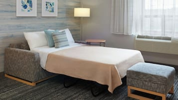 Une chambre d’hôtel avec un lit, une petite table, une lampe et des œuvres d’art accrochées au mur.
