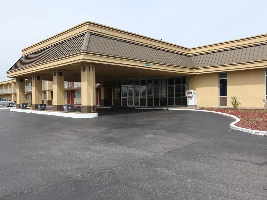 A hotel with a covered entrance, a parking lot, and a FedEx mailbox.