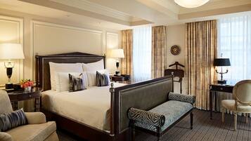 A hotel room with a large bed, a bench, a desk, and a chair.