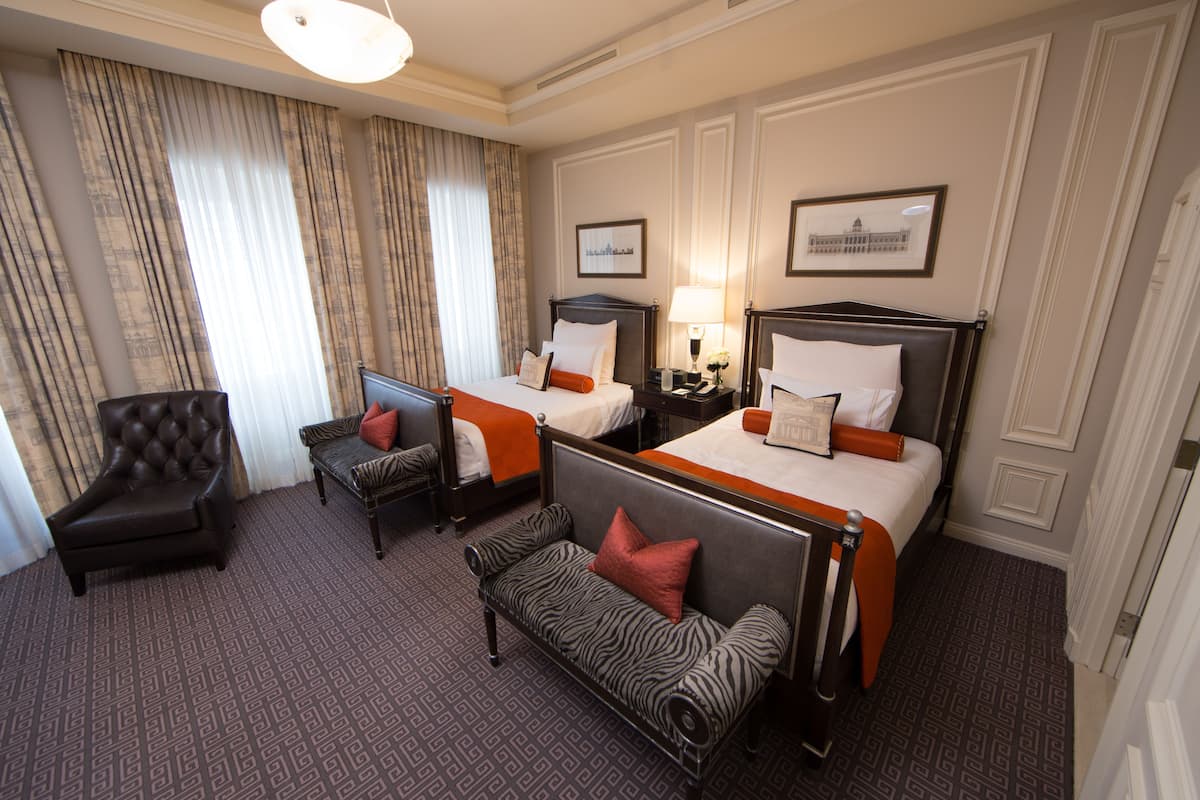 A hotel room with two beds, a sofa, a chair, and a small table.
