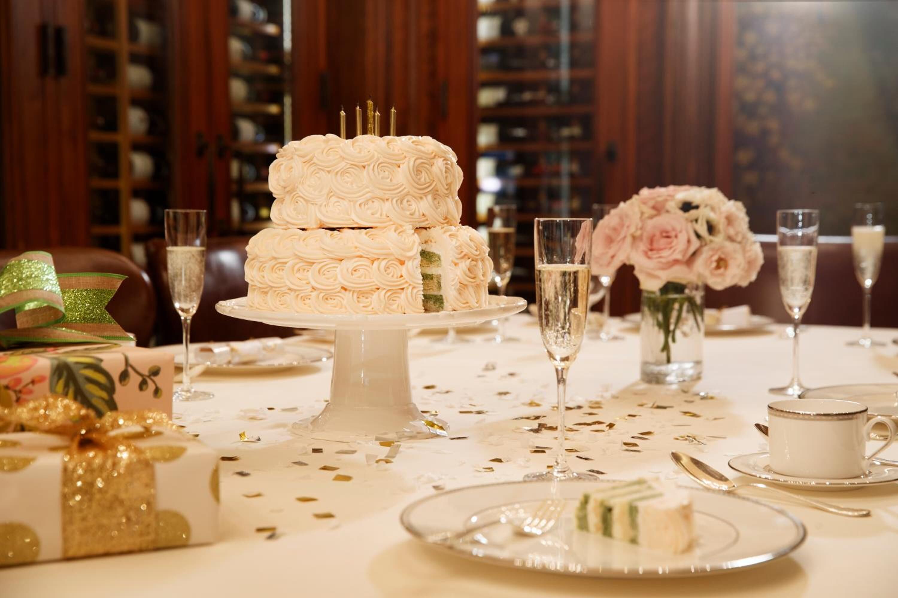 Ein festlich gedeckter Esstisch mit einer mehrstöckigen weißen Torte, Champagnergläsern und floralen Dekorationen.