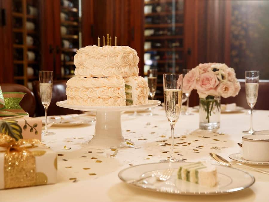 Ein festlich gedeckter Esstisch mit einer mehrstöckigen weißen Torte, Champagnergläsern und floralen Dekorationen.