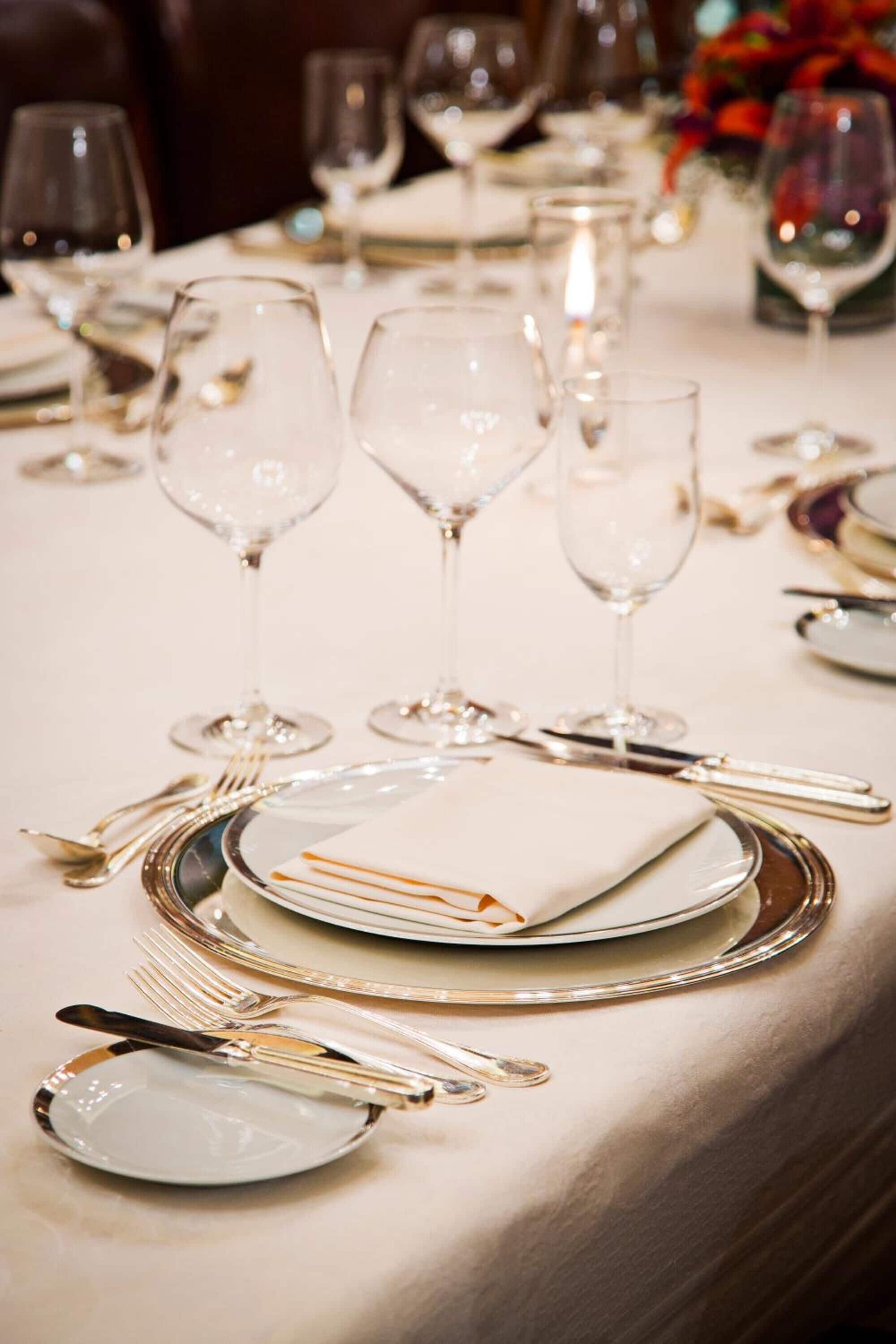 A table set for a formal dining experience with clear glassware, silverware, and white plates.