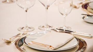 Une table dressée pour un repas formel, avec de la vaisselle en verre transparent, des couverts en argent et des assiettes blanches.