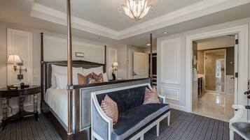 A spacious bedroom with a four-poster bed, a dark blue sofa, and a chandelier.