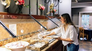 A buffet area with a sign instructing not to waste food, a woman serving herself, and decorative flowers on the wall. - Millennium Hotel Durham (Durham)