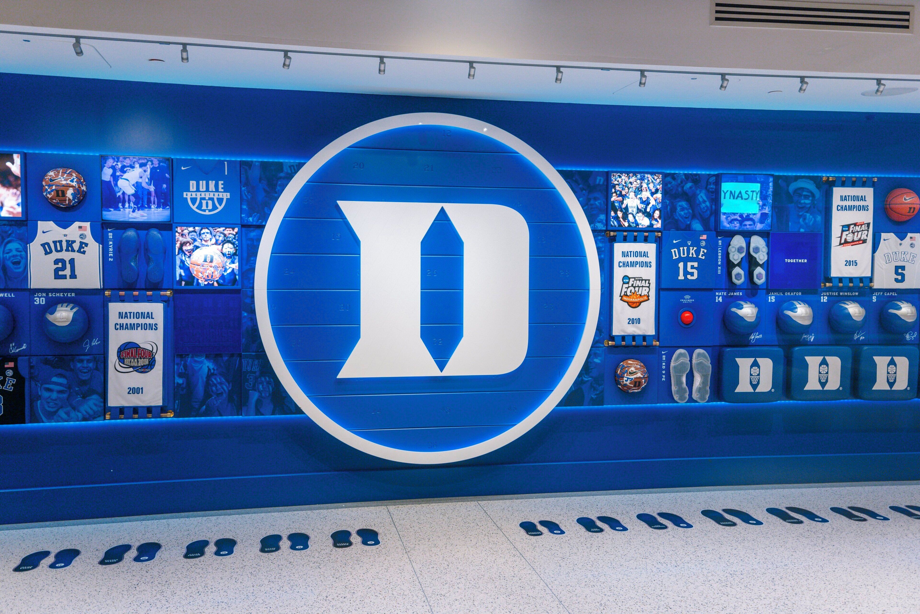 A wall with a large blue and white logo, surrounded by various sports memorabilia and trophies.