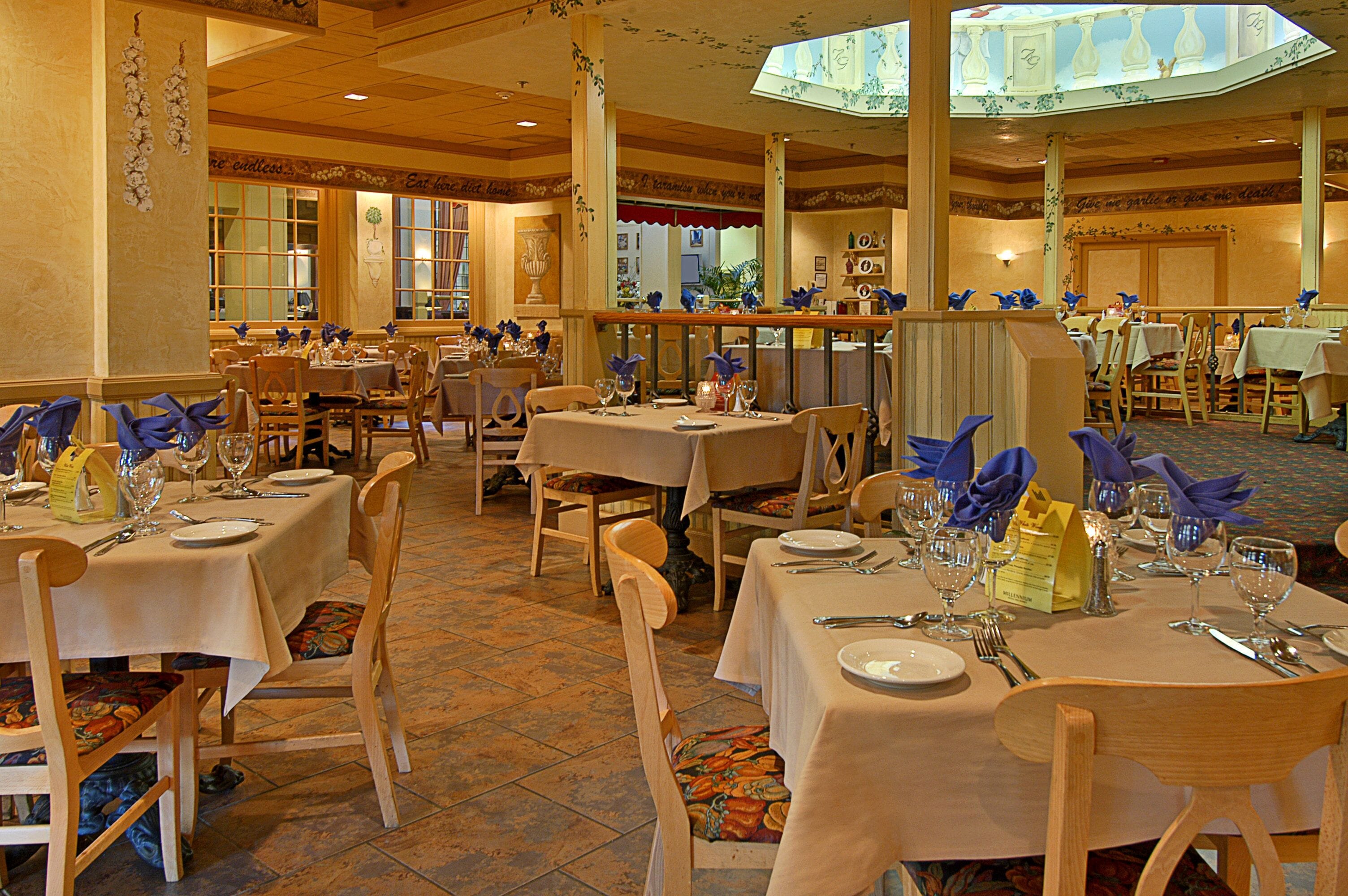 A restaurant with multiple tables set for dining, wooden chairs, and a tiled floor.