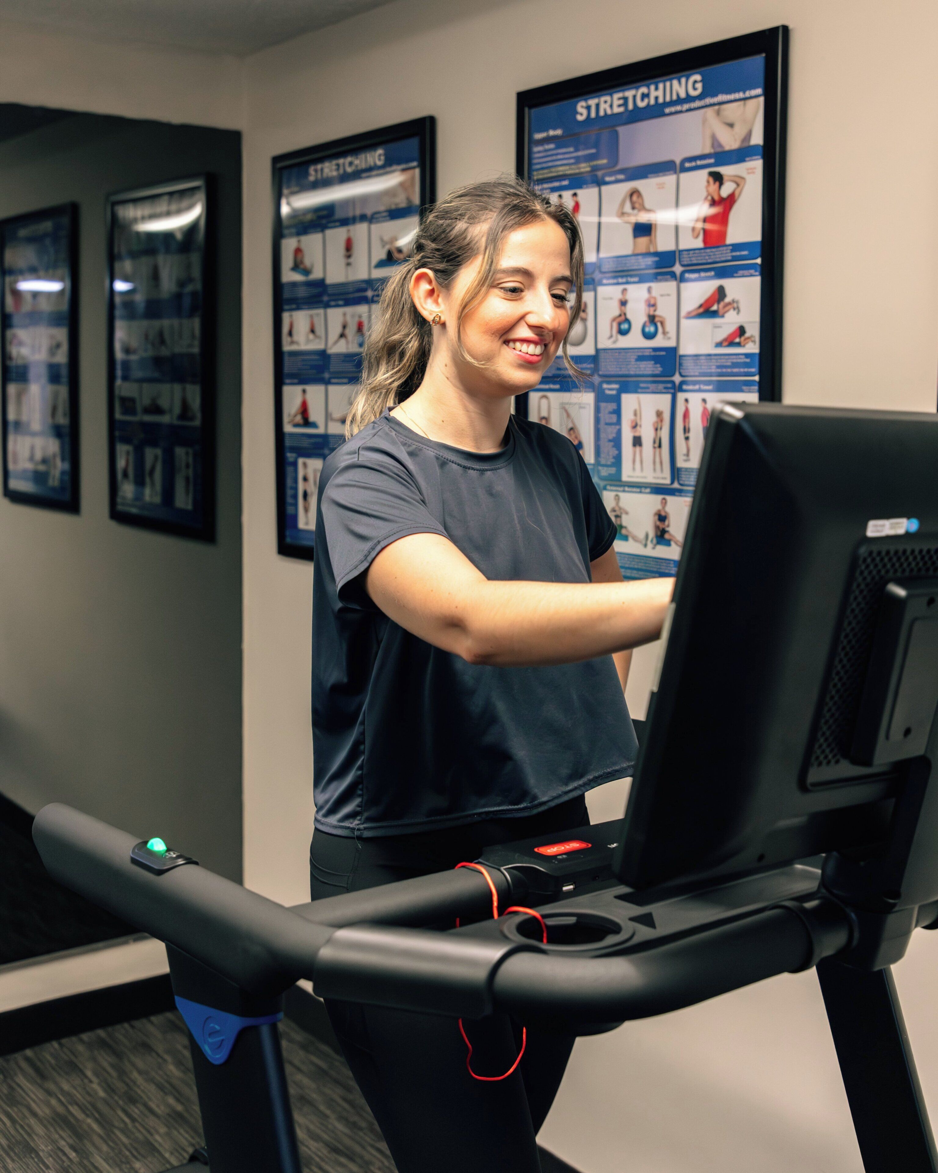 A person using a treadmill in a gym with exercise posters on the wall.