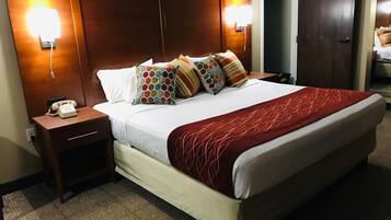 Ett hotellrum med en stor säng, en telefon vid sängen och två väggmonterade lampor.