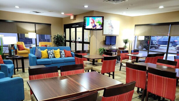 A hotel lobby with a blue sofa, red chairs, and a television on the wall. - Comfort Inn, Erie - Near Presque Isle (Erie)