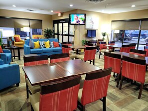 A hotel lobby with a blue sofa, red chairs, and a television on the wall. - Comfort Inn, Erie - Near Presque Isle (Erie)