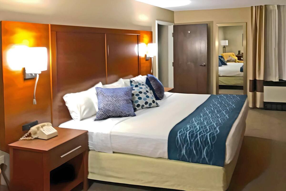 Ein Hotelzimmer mit einem großen Bett, einem Nachttisch und einem Telefontisch.