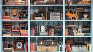 Una estantería llena de libros, marcos con fotografías y objetos decorativos.