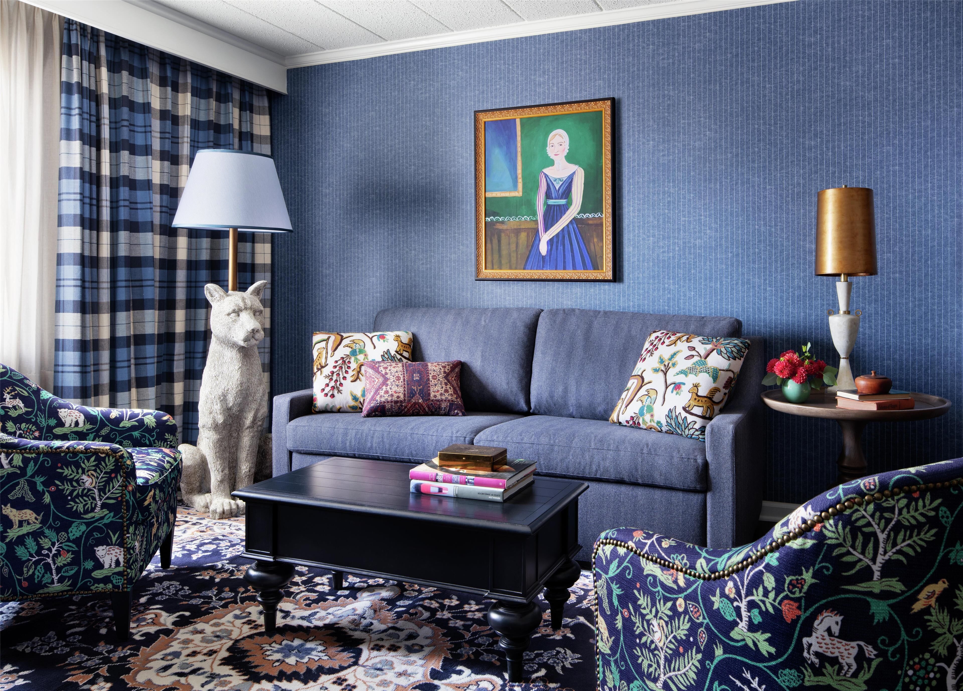 A living room with a sofa, patterned armchairs, a coffee table, and a decorative sculpture.