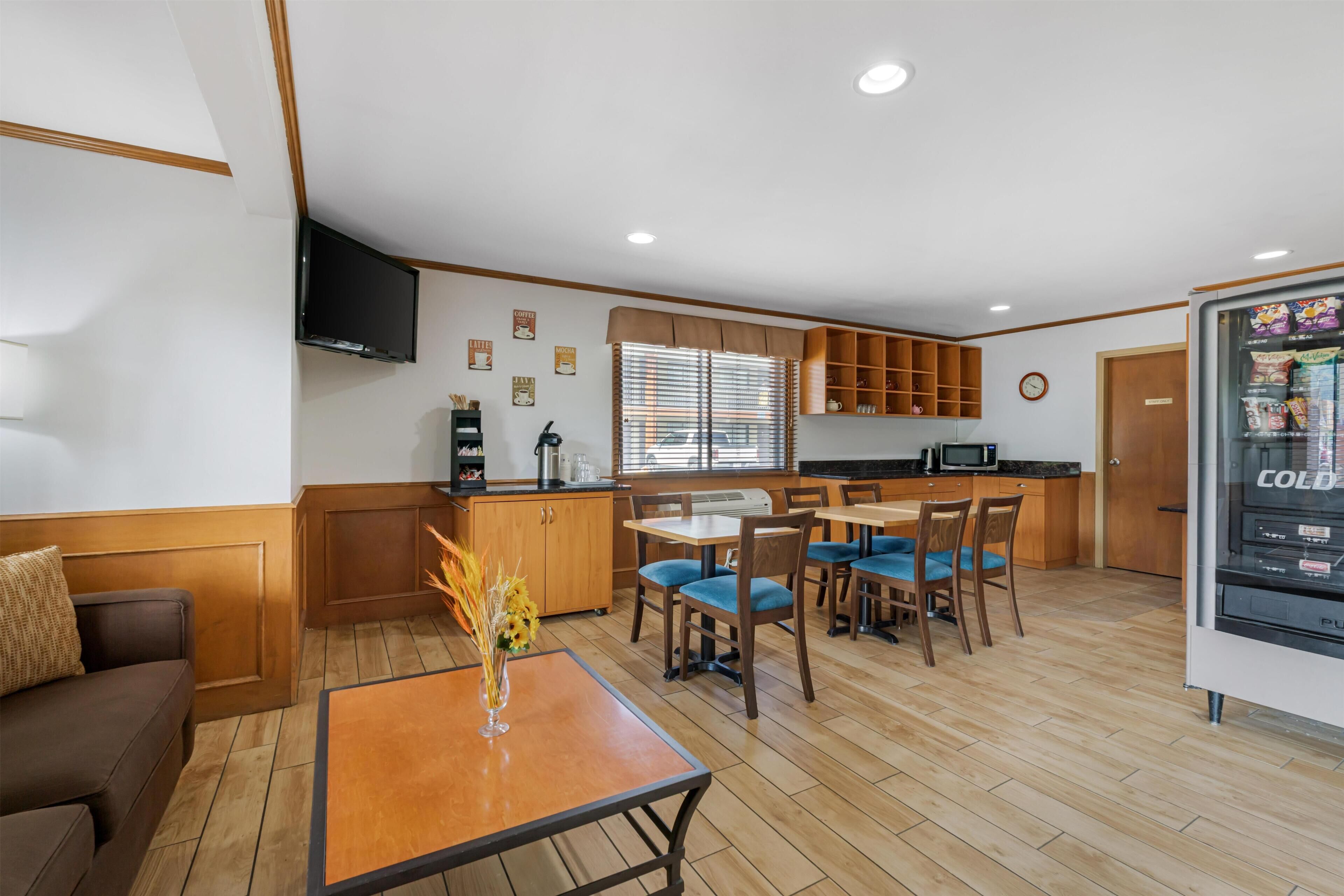A compact living space with a kitchenette, dining area, and a TV mounted on the wall.