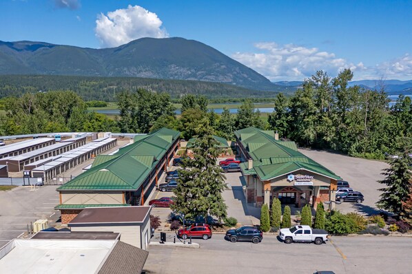 Un motel con varias habitaciones, estacionamiento y vistas a montañas y un lago.