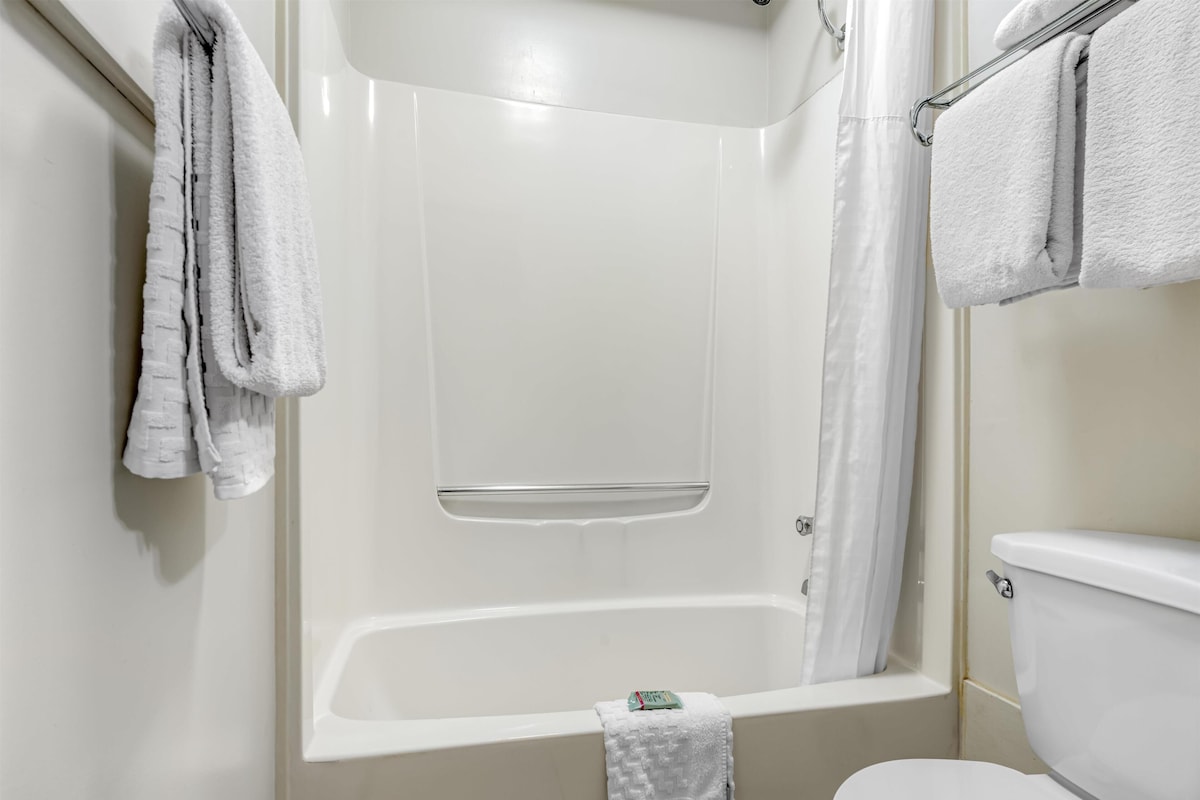 A bathroom with a bathtub, toilet, and towel rack.