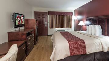 A hotel room with a bed, a television, a dresser, and a door.