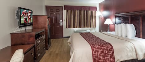 A hotel room with a bed, a television, a dresser, and a door.