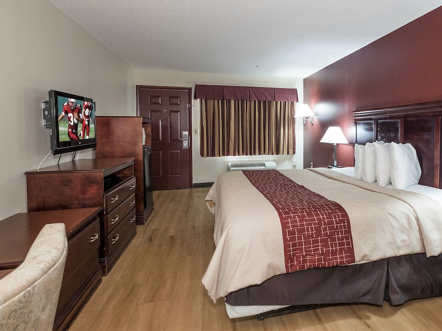 Ein Hotelzimmer mit Bett, Fernseher, Kommode und Tür.