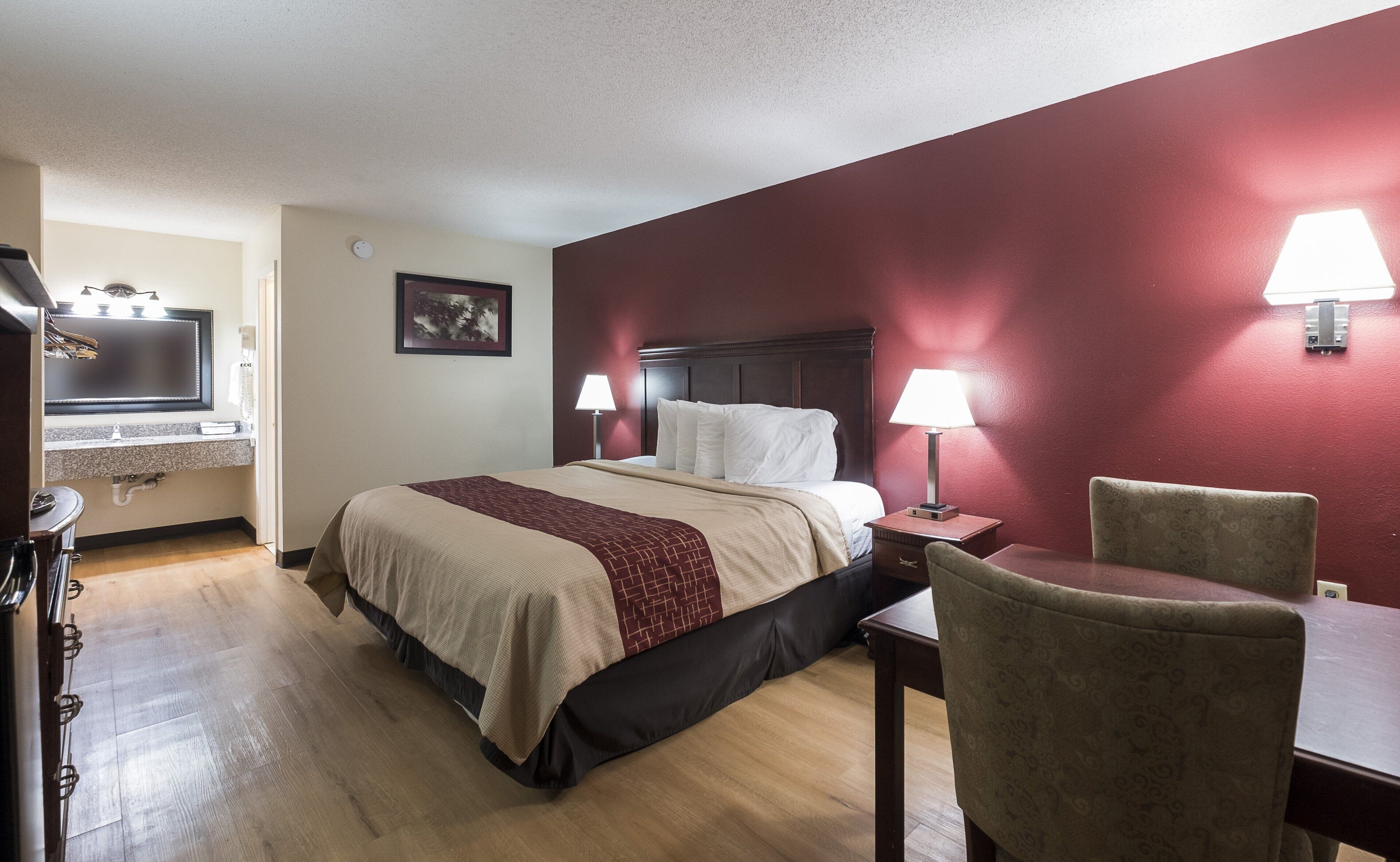 A hotel room with a bed, bedside lamps, a desk, and a chair.